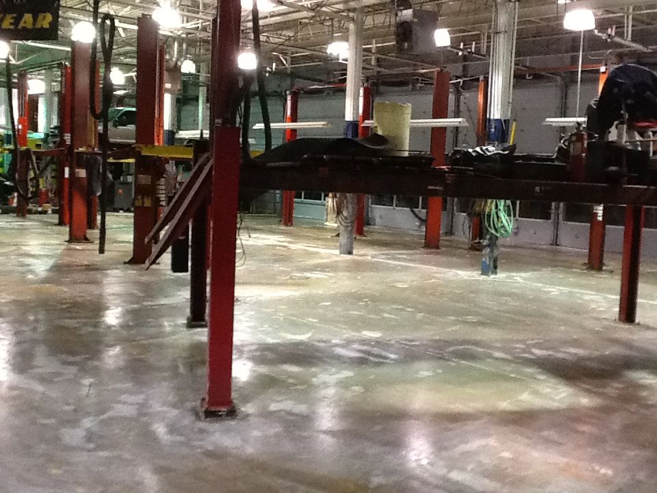 Clean, gray non-slip epoxy flooring in a well-lit car dealership service bay.